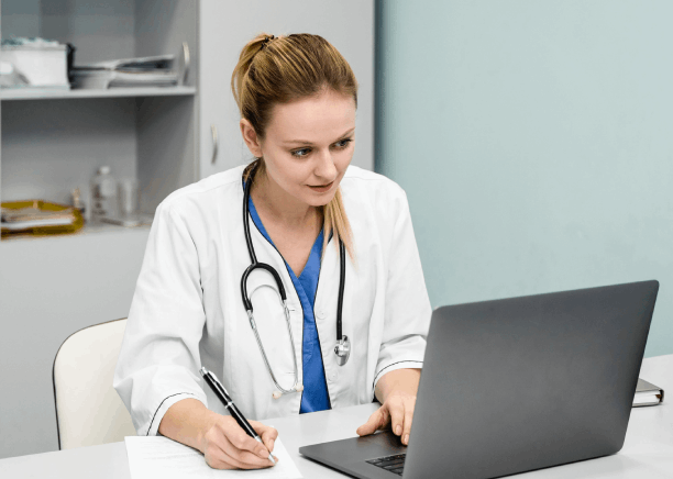 A French doctor reviews a patient's medical record on a laptop, with French Translation in Florida for medical purposes.